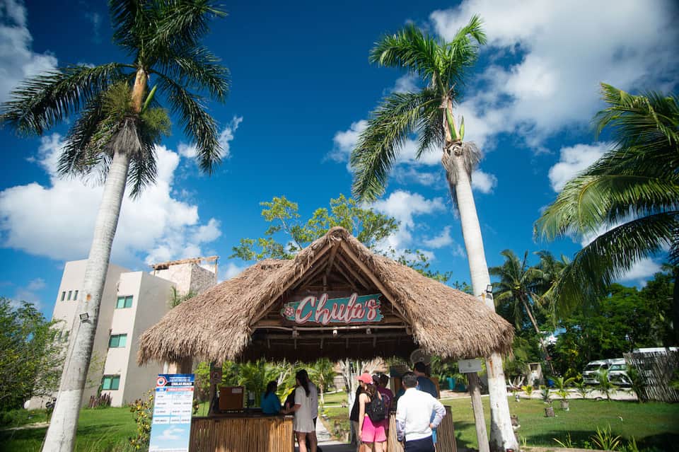 Thatched-roof beach bar called Chulia's with palm trees and modern hotel building in background