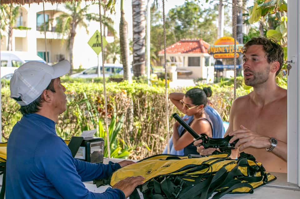Water sports instructor explaining equipment to guests at beachfront activity area