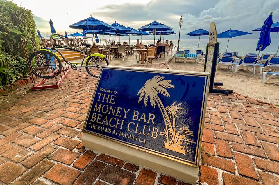 The Money Bar Beach Club sign at beachfront venue with blue umbrellas and ocean views in Marbella