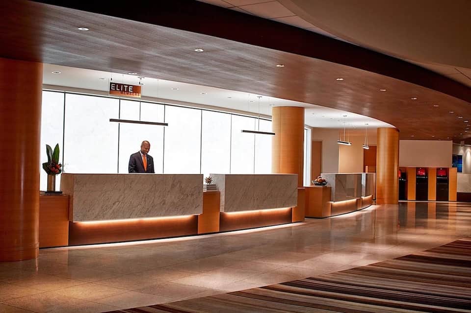 Hotel reception desk with curved marble design, warm lighting, and concierge staff
