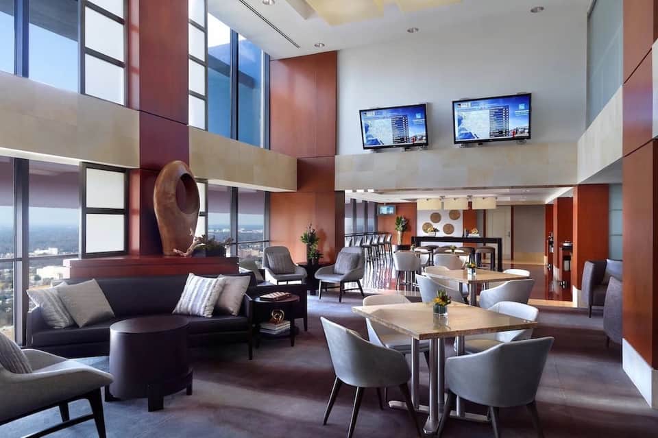 High-rise hotel lounge with panoramic city views, terracotta accent walls, and contemporary seating areas