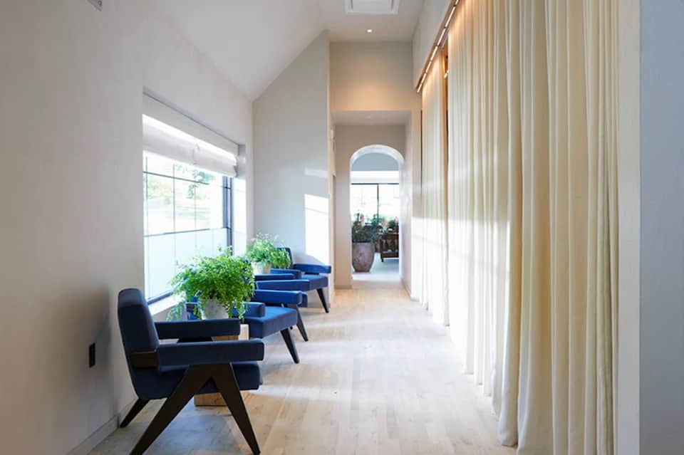 Bright hallway with blue accent chairs, natural light, and archway leading to additional seating