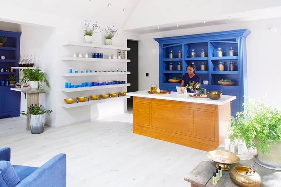 Modern spa retail space with blue cabinetry, white shelves, and wooden reception counter
