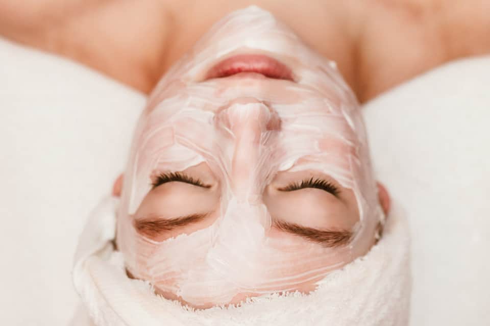 Person wearing pink face mask treatment with eyes closed for spa skincare