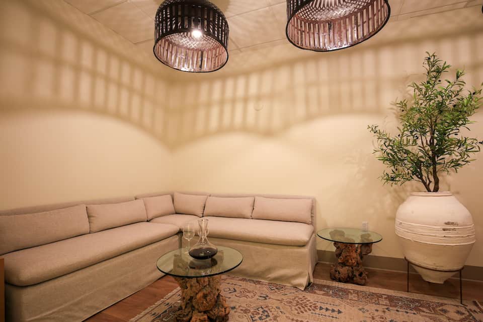 Modern spa lounge with beige sectional sofa, decorative pendant lights, and potted plant