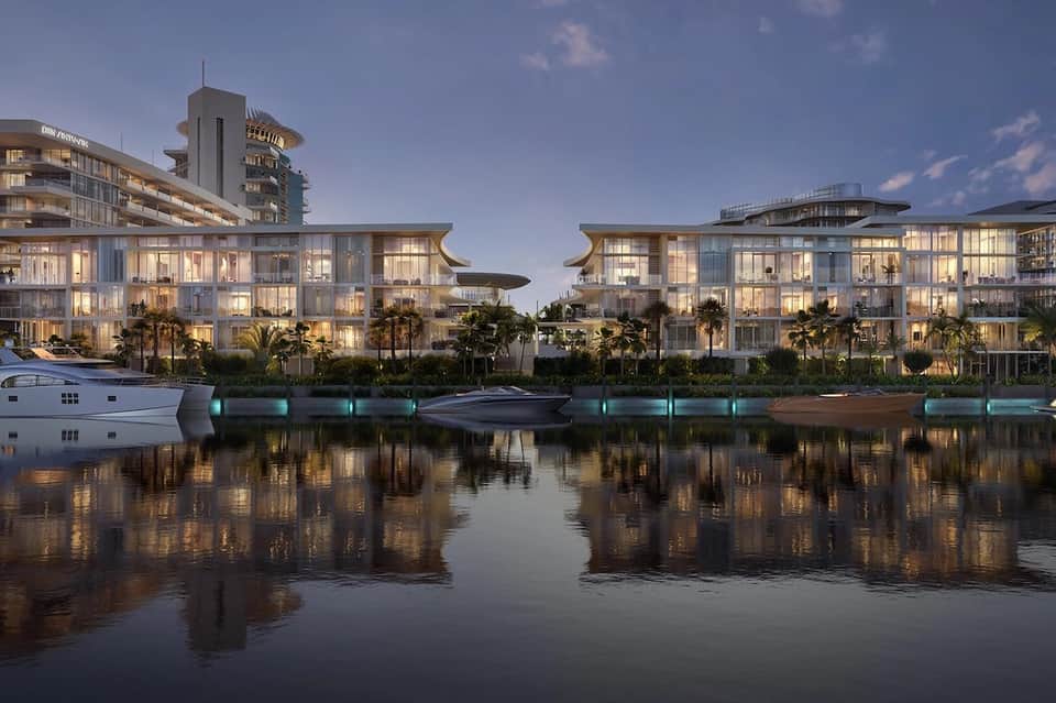 Contemporary waterfront resort buildings reflected in calm water at dusk with palm trees