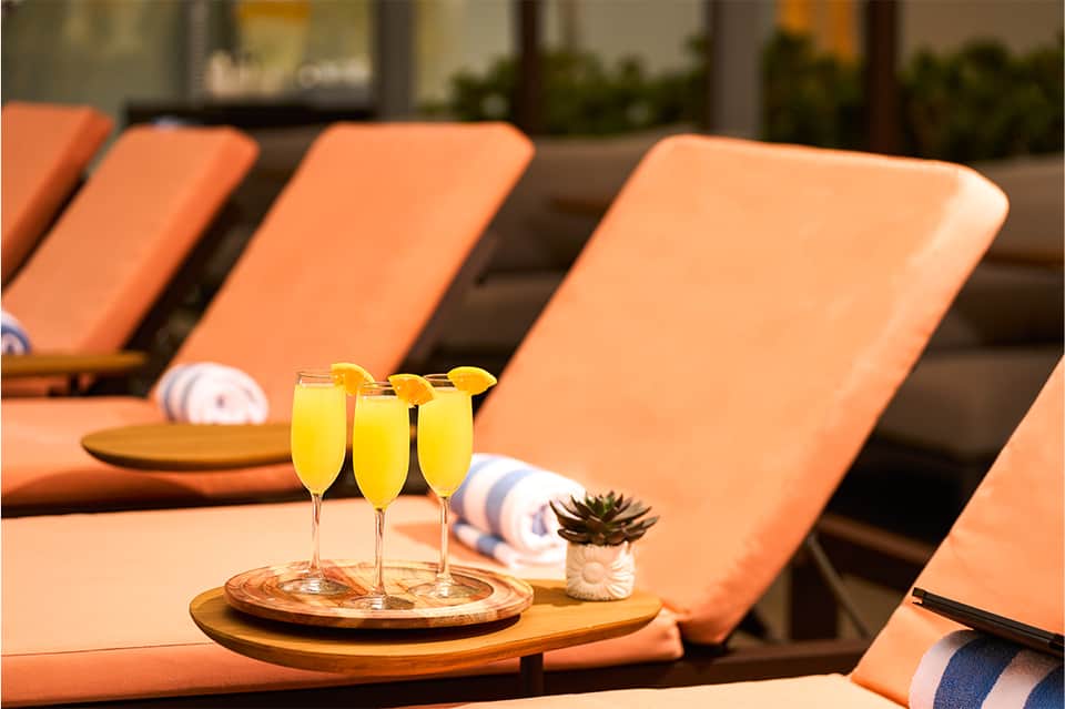 Poolside lounge chairs with orange cushions and welcome drinks