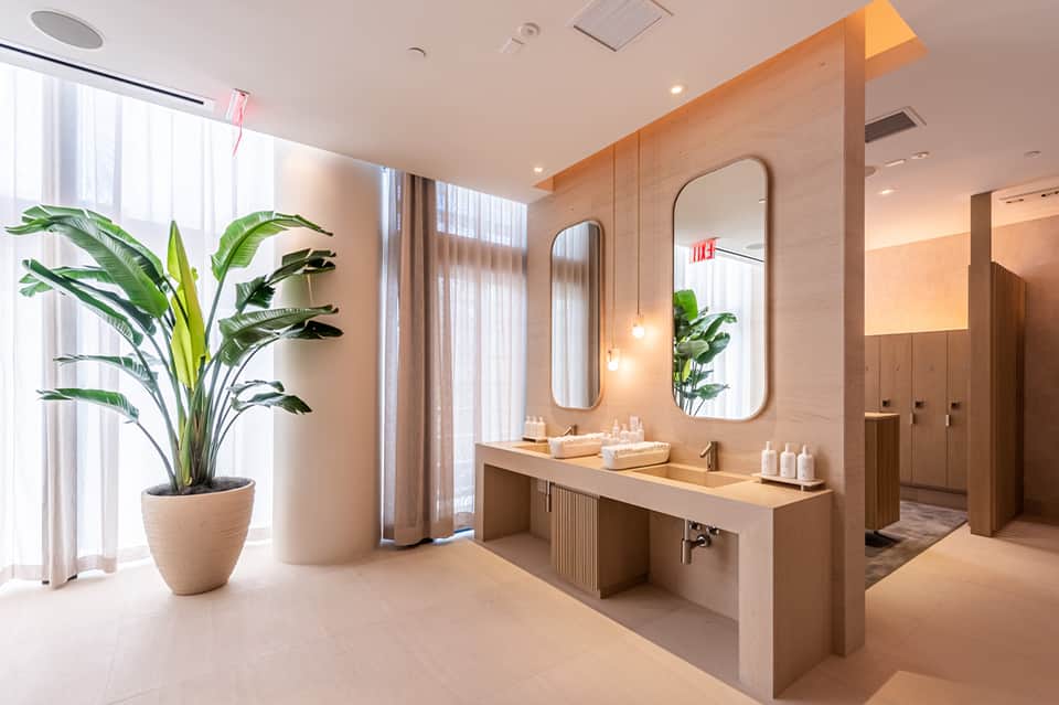 Contemporary spa bathroom with dual vanity sinks, large mirrors, wooden accents, plants, and natural lighting