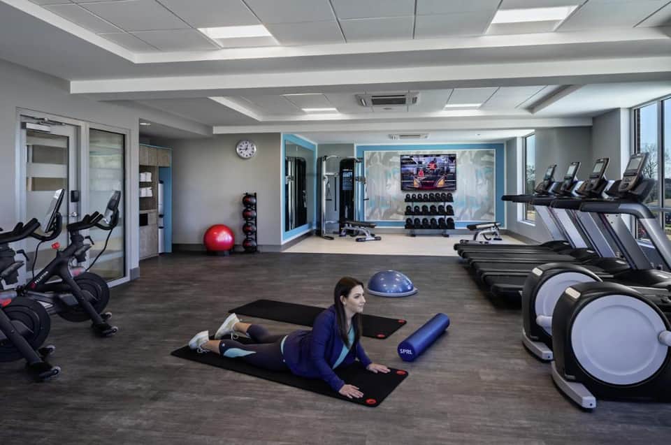 Modern fitness center with cardio equipment, weights, and exercise machines with mirrored walls
