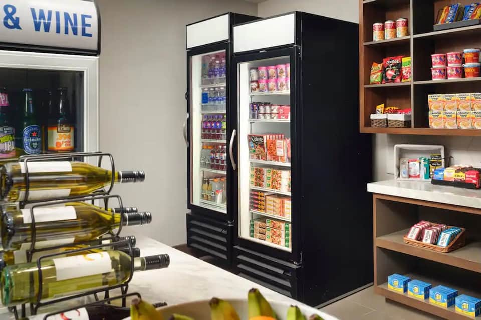 Modern convenience store interior with refrigerated beverage coolers, wine display, and stocked shelves