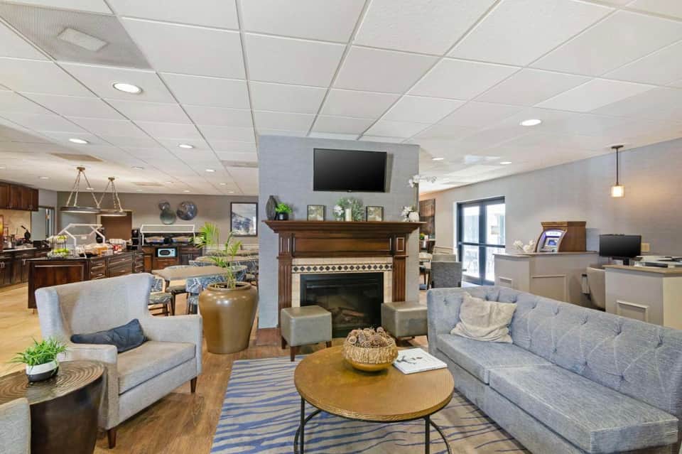 Spacious hotel lobby lounge with fireplace, gray sofas, wood furnishings, and contemporary design