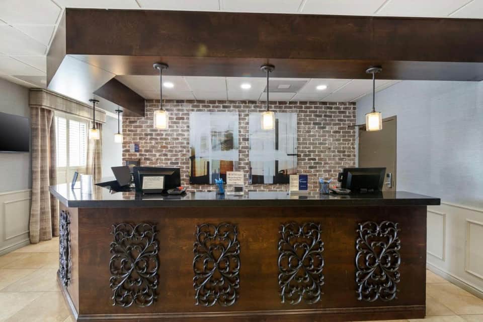 Hotel reception desk with ornate dark wood panels and brick accent wall with pendant lighting