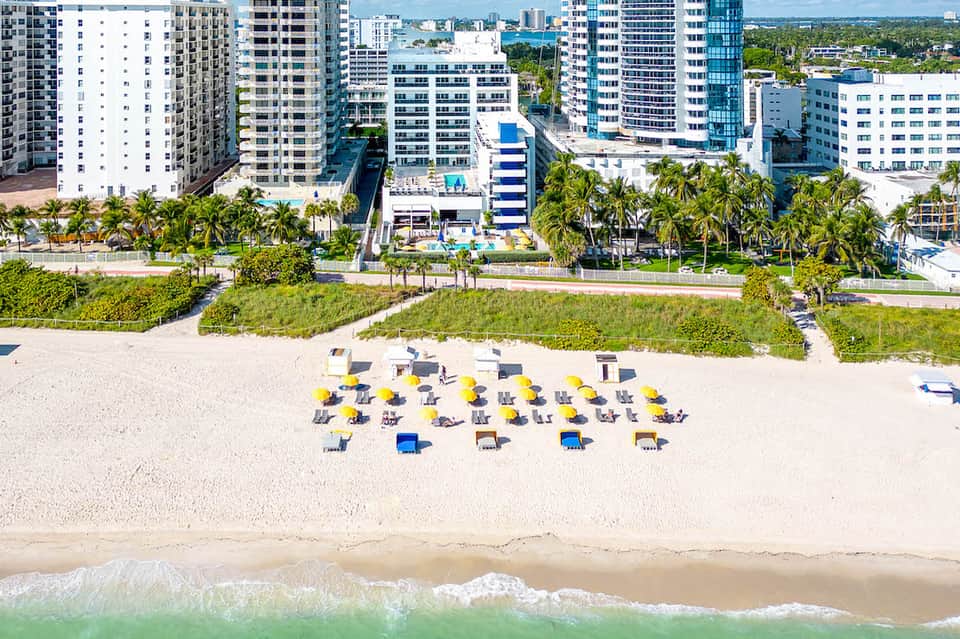 Aerial view of beachfront resort with rows of lounge chairs and umbrellas on sand