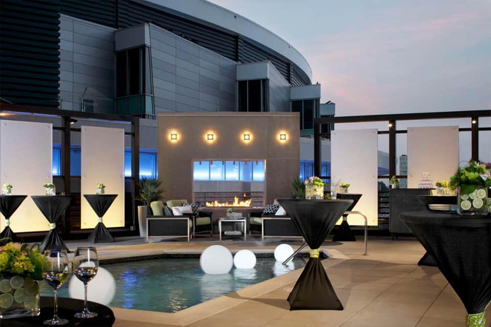 Upscale resort pool deck at dusk with fireplace, lounge seating, and modern architecture