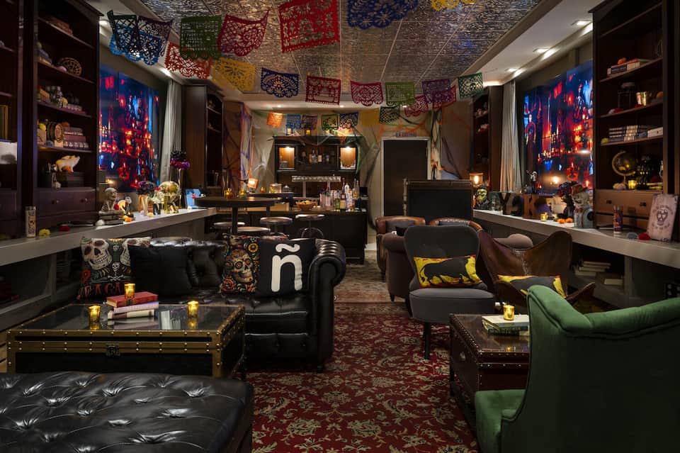 Eclectic lounge with dark furniture, colorful pendant decorations, neon artwork, and ornate shelving