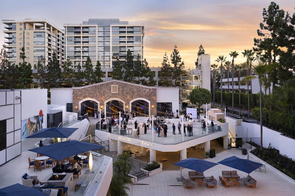 Urban resort courtyard with arched brick structure, gathering spaces, and surrounding buildings