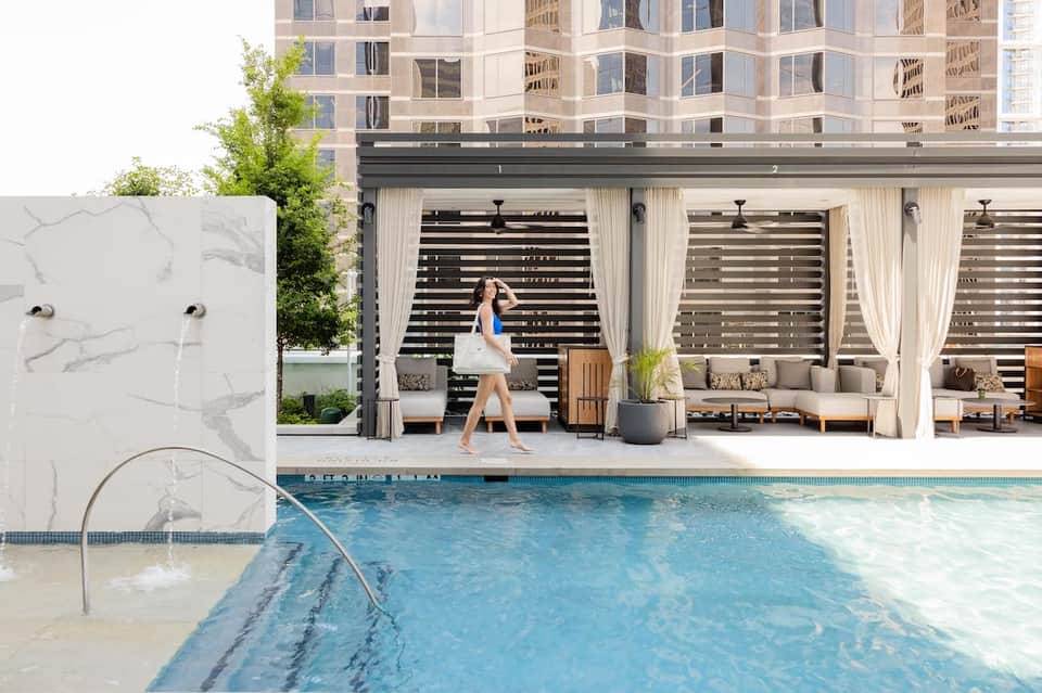 Indoor pool area with modern cabanas, curtains, and contemporary resort architecture