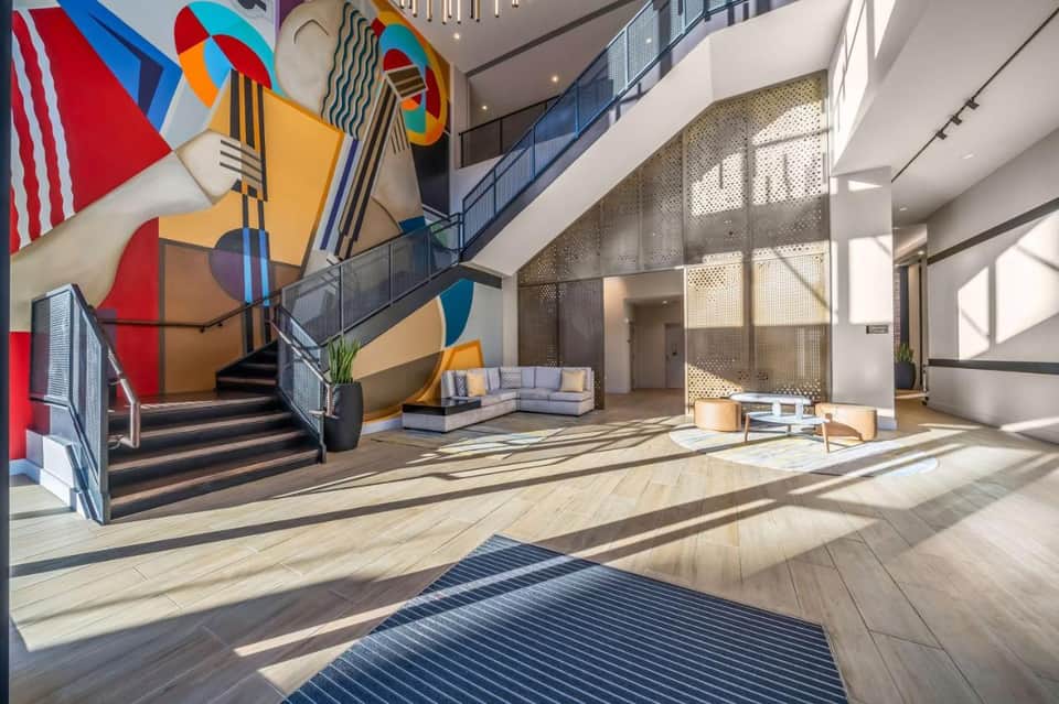 Bright hotel lobby with colorful geometric wall art, stairs, and contemporary furniture