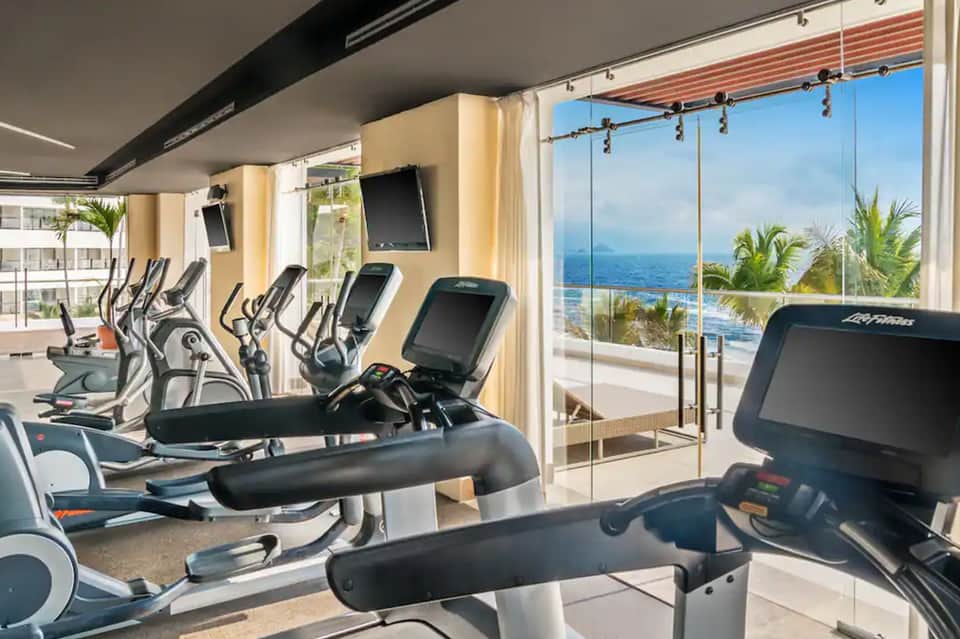 Oceanview fitness center with elliptical machines, treadmills, and large windows overlooking the sea