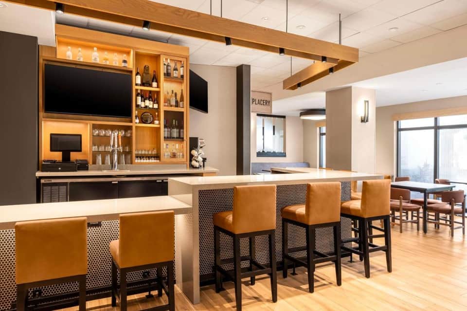 Modern hotel bar and lounge with wood accents, bar seating, and ambient lighting