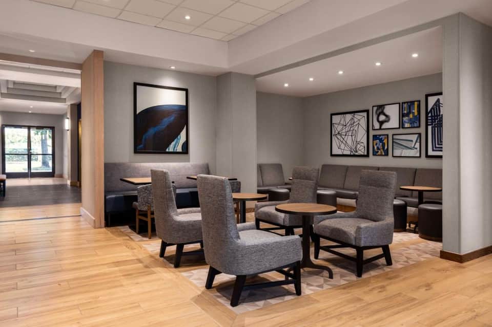 Upscale hotel lounge with gray armchairs, wood tables, and contemporary artwork