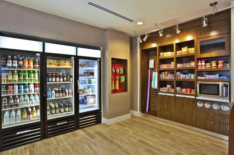 Hotel market with refrigerated beverage cases and wooden shelving displaying snacks