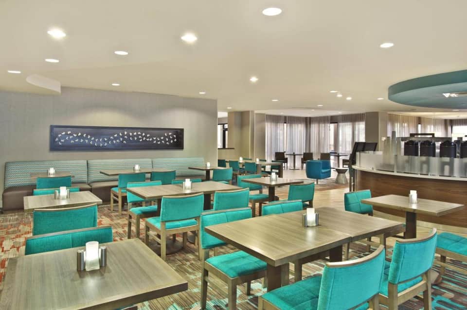 Elegant hotel restaurant with turquoise seating, natural lighting, and curved architectural details