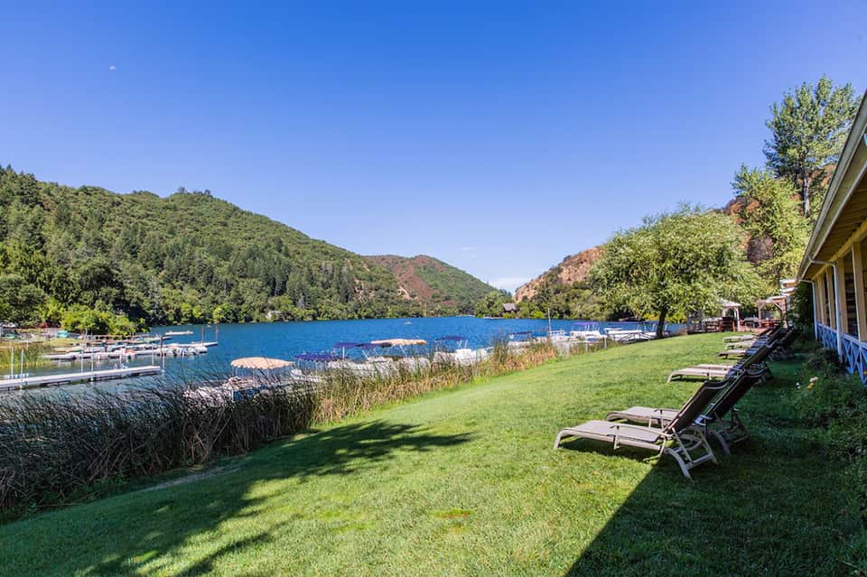 Scenic lakeside resort grounds with lounge chairs, green lawn, and forested mountains