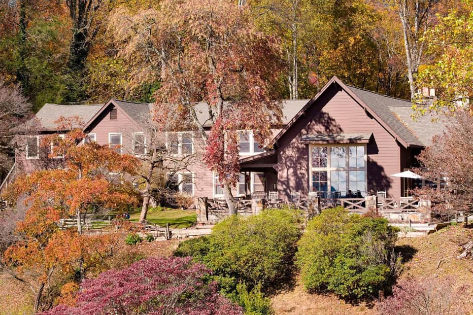 Residential house with autumn foliage, pink siding, white trim, and manicured landscaping