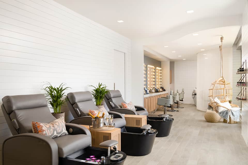 Luxury spa treatment room with massage chairs, mirrors with lighting, and modern wellness decor