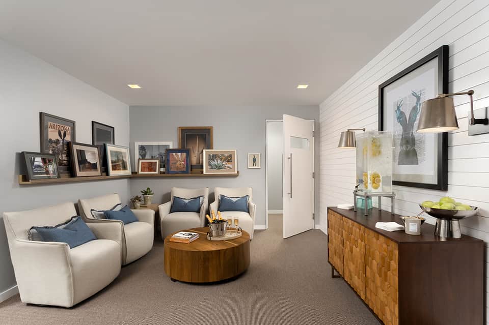Modern lounge area with cream armchairs, wooden coffee table, and framed artwork on walls