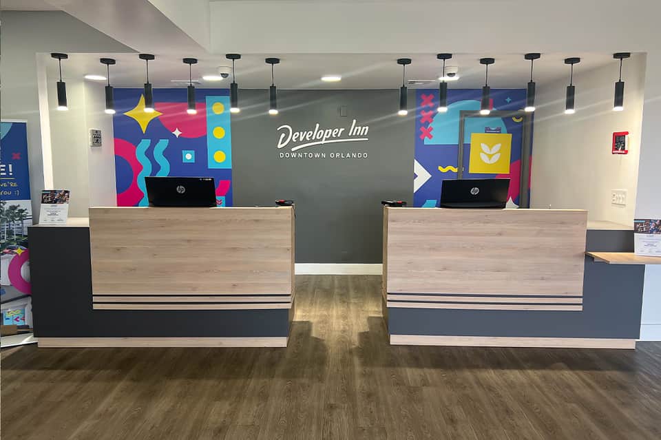 Modern hotel check-in desk with colorful abstract murals, dual reception counters, and contemporary lighting