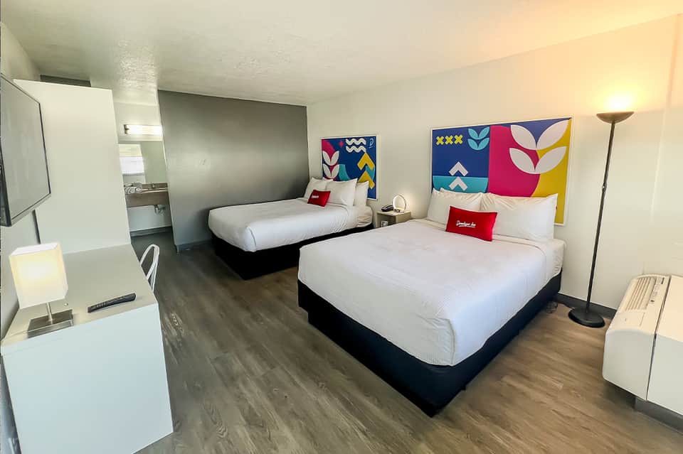 Modern hotel room with two queen beds, colorful geometric headboards, and contemporary furnishings