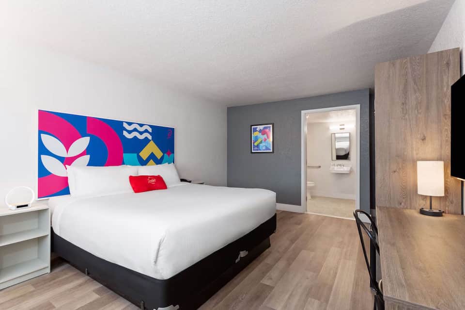 Contemporary hotel bedroom with colorful headboard art and modern furnishings
