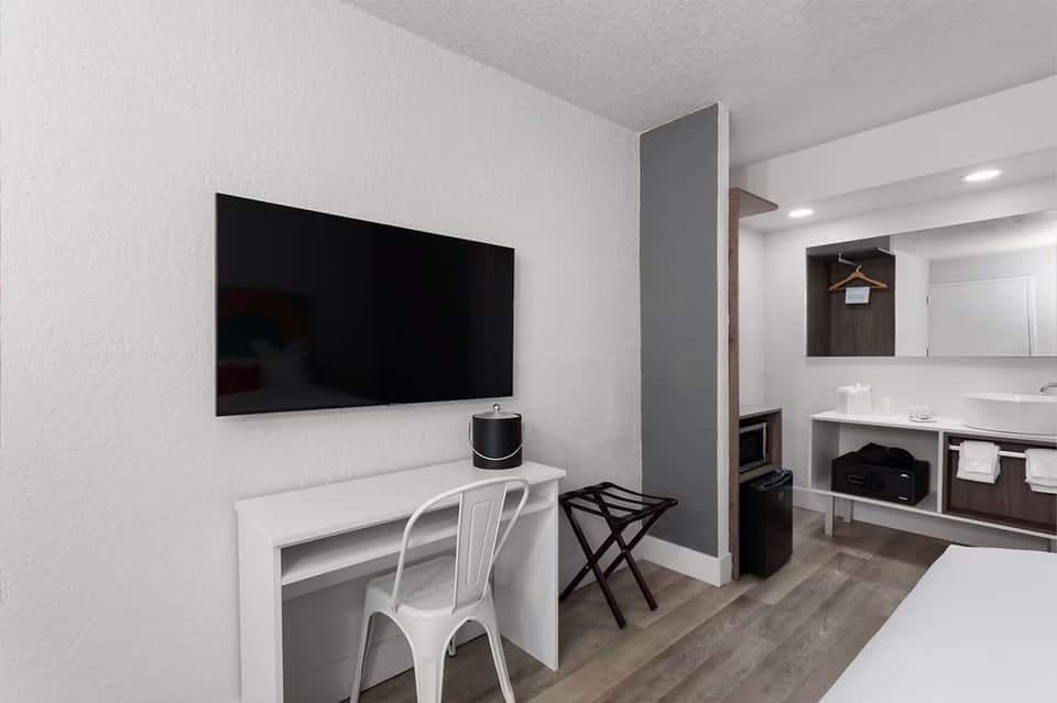 Hotel room workspace with wall-mounted TV, desk, and ensuite bathroom visible