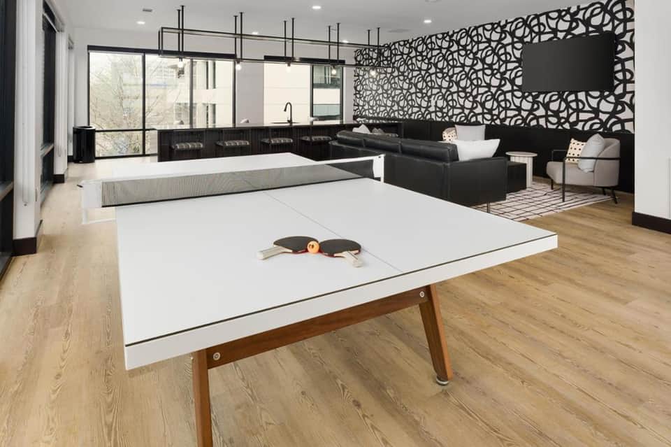 Modern recreation room with ping pong table, black sofa, fireplace, and decorative wall paneling