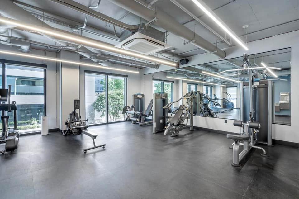 Bright, modern fitness center with exercise equipment, large windows, and polished concrete flooring