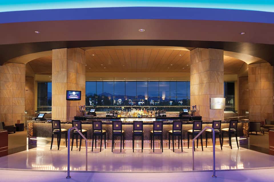 Upscale bar with modern curved design, city skyline view, and illuminated flooring