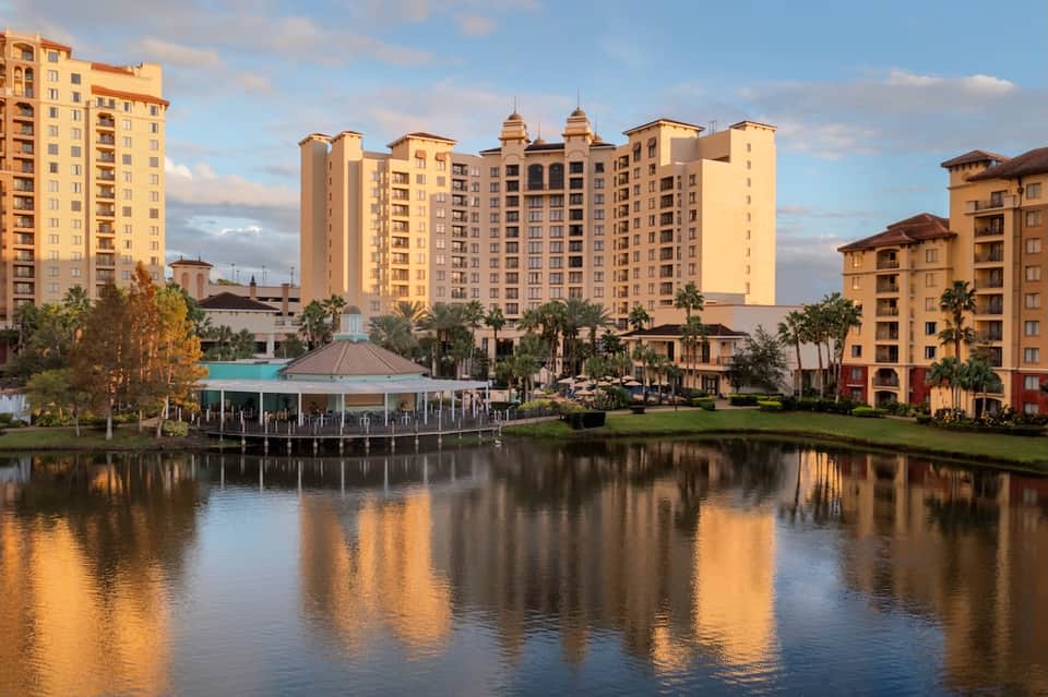 Multi-story resort buildings reflected in calm waterway with manicured grounds