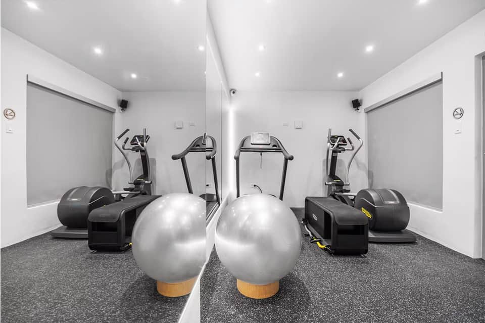 Modern fitness center with treadmills, exercise bikes, and stability balls on gray flooring