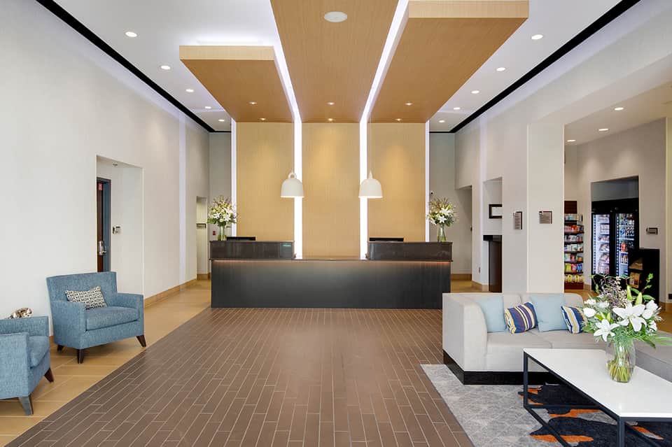 Contemporary hotel lobby with wood ceiling details, modern reception desk, and seating areas