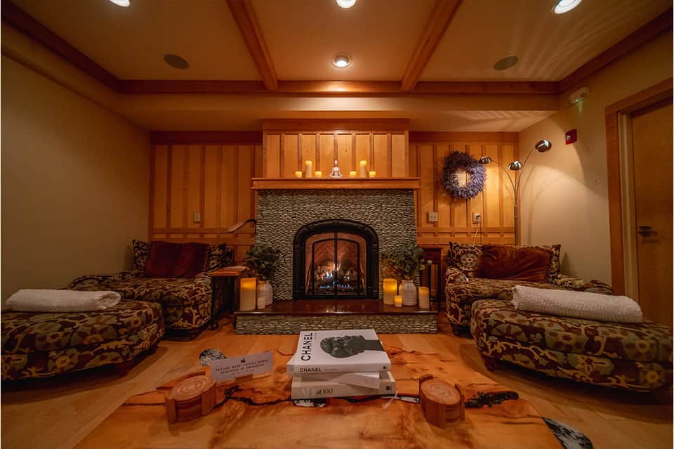 Upscale lounge with fireplace, ornate wooden paneling, patterned seating, and candlelit ambiance