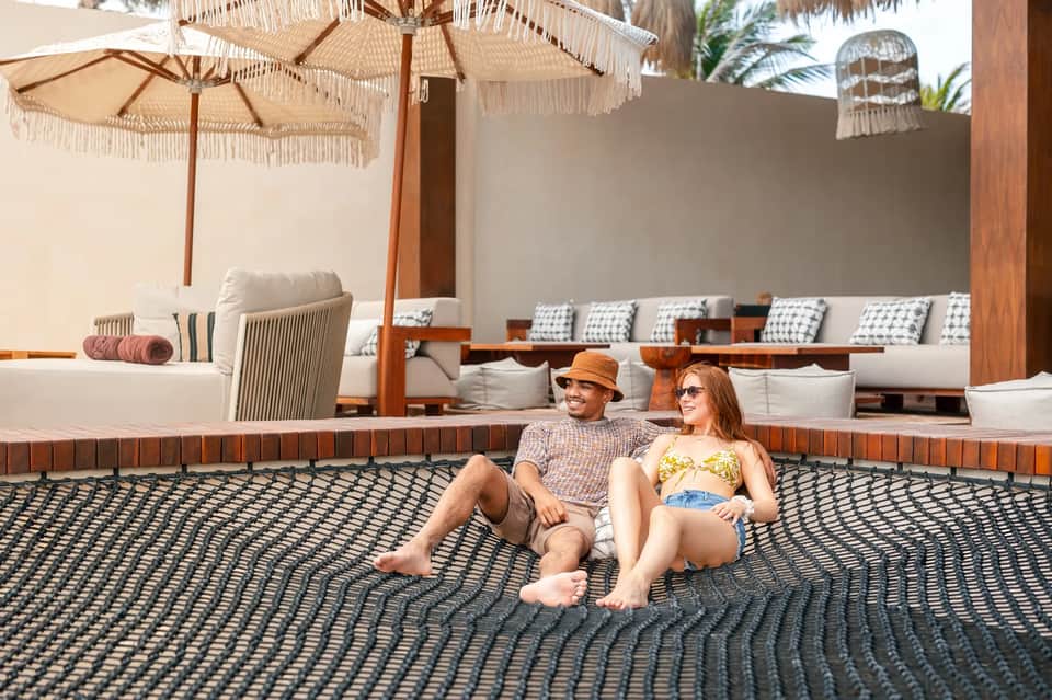 Couple sitting on patterned outdoor deck with lounge furniture and fringe umbrellas