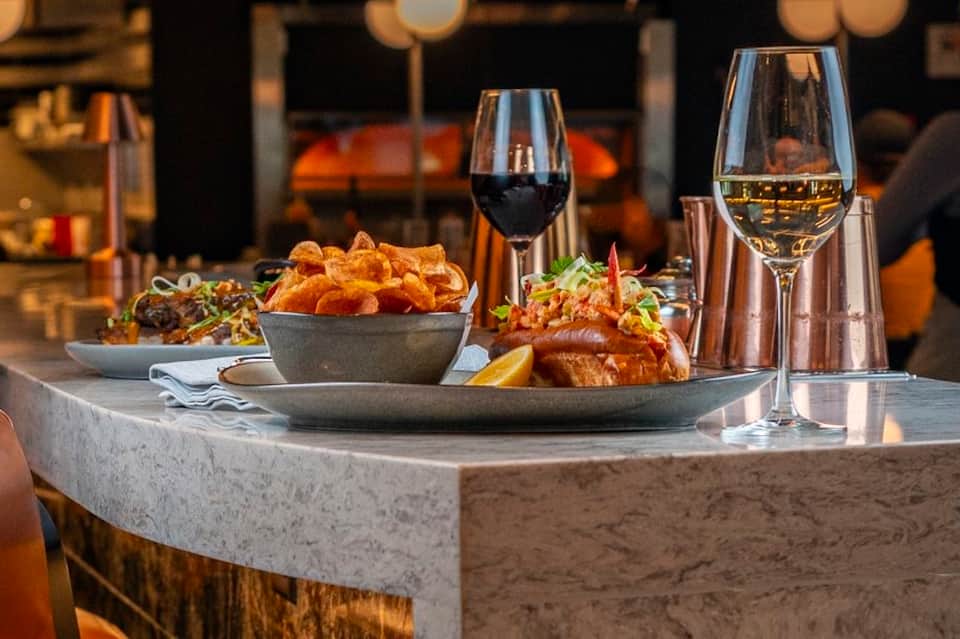 Fine dining table with wine glasses, fried food, and ocean view backdrop