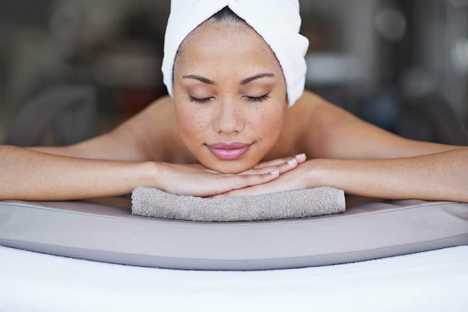 Woman relaxing in spa with white towel wrapped around head at poolside