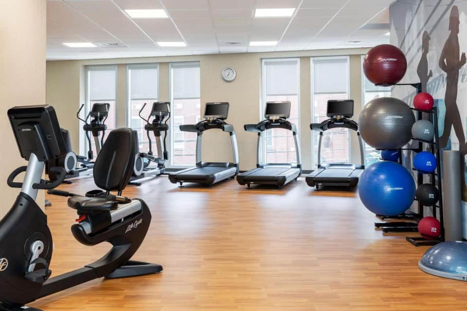 Modern fitness center with treadmills, stationary bikes, exercise balls, bright windows