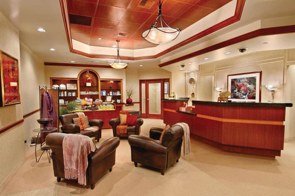 Elegant hotel spa reception area with red wood accents and leather seating