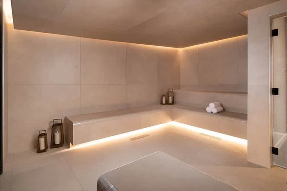 Luxurious spa bathroom with sunken soaking tub, ambient lighting, cream tiles, and minimalist design