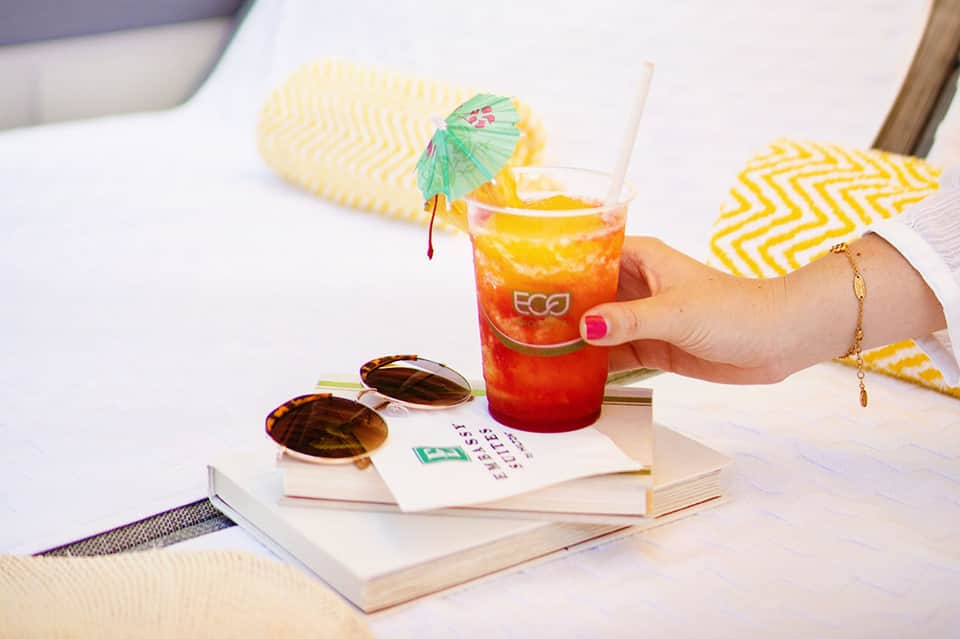 Woman's hand holding colorful tropical cocktail with umbrella garnish on resort table