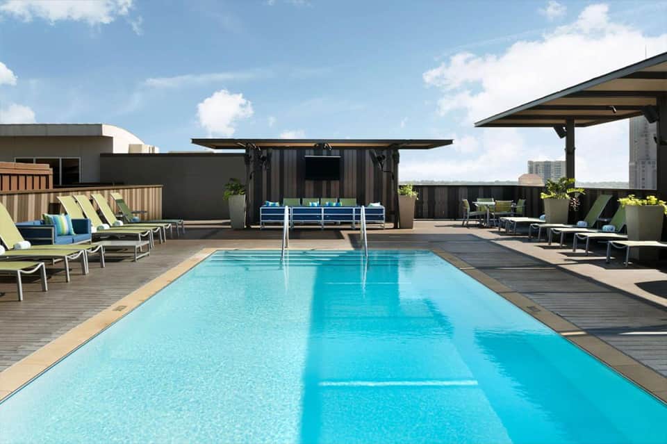 Rooftop pool with modern shade structures, lounge chairs, and city skyline views
